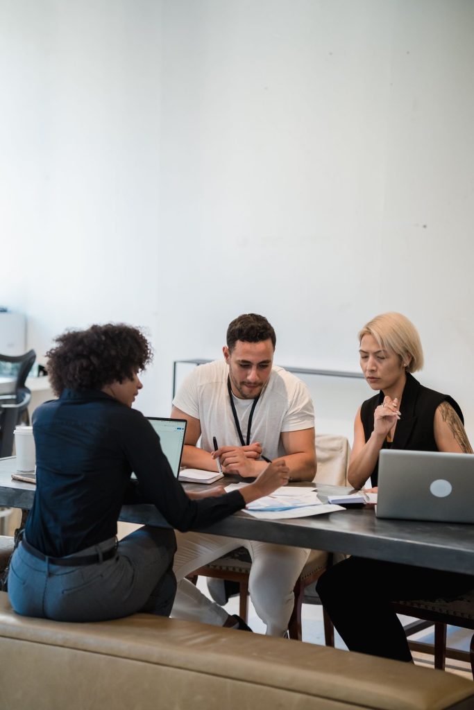 Three colleagues collaborating around a laptop in a bright office